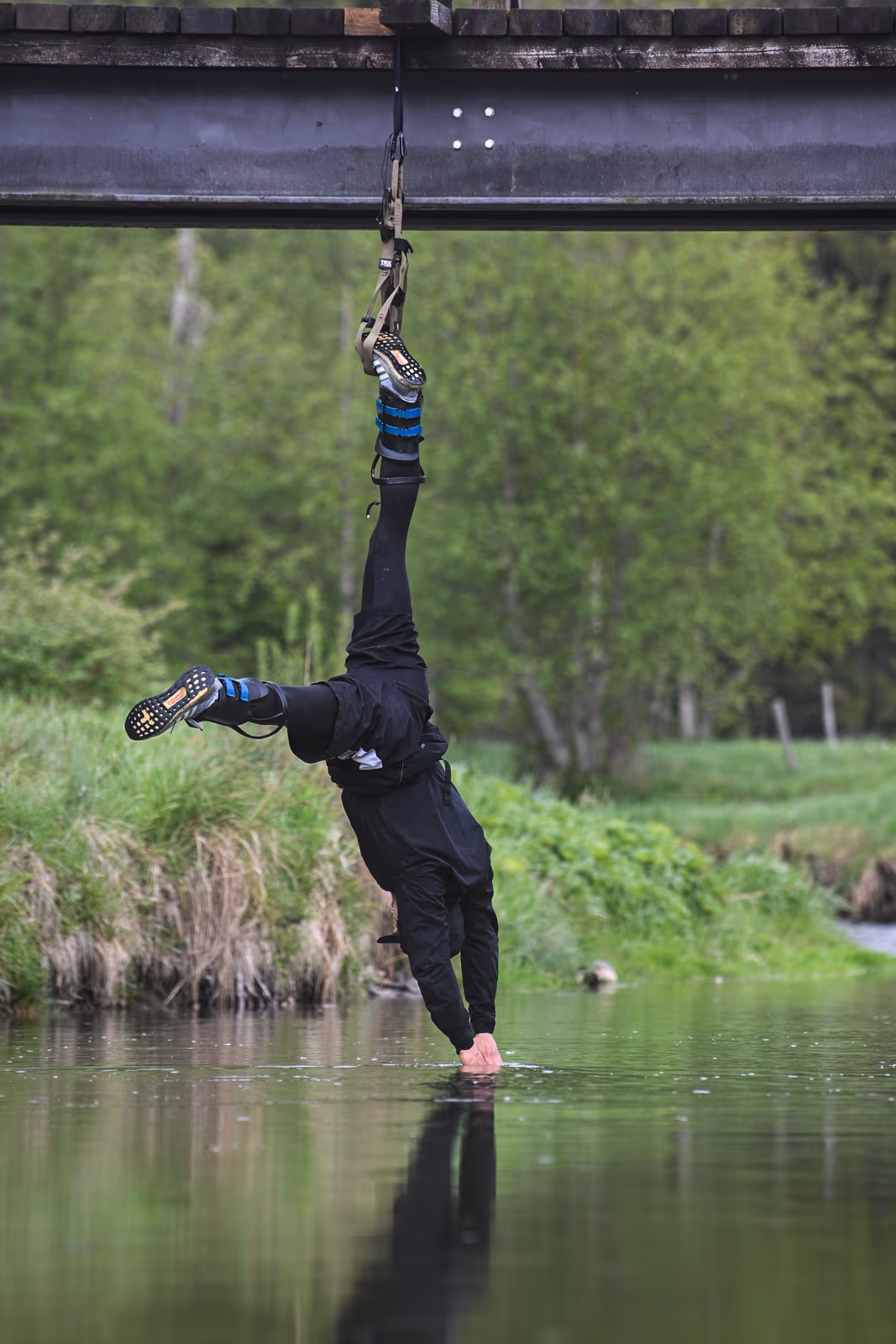 Aaron Schwägerl berührt im TRX-Band hängend die Wasseroberfläche unter der Brücke